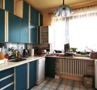 Eine Küche in einem Einfamilienhaus mit blauer Küchenzeile und großem Fenster, die Atmosphäre eines Zuhauses.