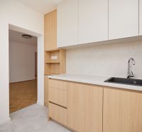 Eine Küchenzeile mit hellen Schränken und einem Boden in Holzoptik, 3-Zimmer-Wohnung.