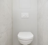 Minimalistisches WC in einer 3-Zimmer-Wohnung mit hellen Fliesen an den Wänden.