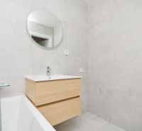 Badezimmer mit Badewanne, Waschbecken und Holzelementen in einer 3-Zimmer-Wohnung.