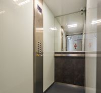 Innenraum eines Aufzugs mit Knöpfen, Edelstahlelementen und Spiegeln in einer 3-Zimmer-Wohnung.