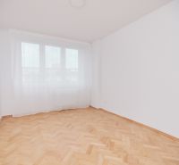 Ein leerer Raum in einer 3-Zimmer-Wohnung mit einem Holzboden und einem großen Fenster.