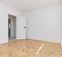 Ein Zimmer mit weißen Wänden und einem Holzboden in einer 3-Zimmer-Wohnung.