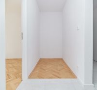 Ein enger Flur mit weißen Wänden in einer 3-Zimmer-Wohnung und einem Boden in Holzoptik.