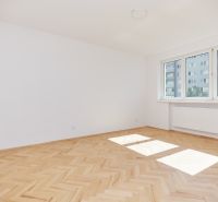 Ein heller Raum mit weißen Wänden und einem Boden in Holzoptik in einer 3-Zimmer-Wohnung.