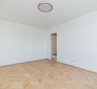 Ein leerer Raum mit Holzboden-Dekor und Blick in die Küche in einer 3-Zimmer-Wohnung.
