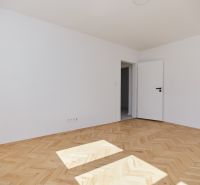 Helles Zimmer mit weißen Wänden und einem Boden in Holzoptik, 3-Zimmer-Wohnung.