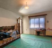 Ein Zimmer in einem Einfamilienhaus mit Teppichboden, einem Sofa und einem Fenster mit Vorhang.