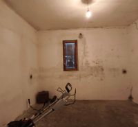 Keller mit Fenster in einem Einfamilienhaus, Wände mit Rissen und einfacher Beleuchtung.