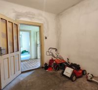 Das Innere eines Einfamilienhauses mit offenen Türen, einem Rasenmäher und Werkzeugen auf dem Boden.
