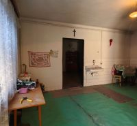 Einfaches Zimmer in einem Einfamilienhaus mit Waschbecken und Vorhängen an den Fenstern.