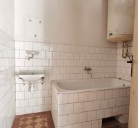 Badezimmer in einem Einfamilienhaus mit Badewanne, weißen Fliesen und einem Wassererhitzer.