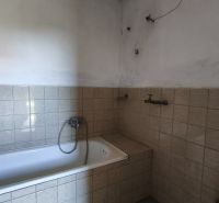 Ein Badezimmer in einem Einfamilienhaus mit einer Badewanne, die mit hellen Fliesen verkleidet ist.