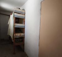 Ein schmaler Flur mit Regalen in einem Einfamilienhaus, einfache Einrichtung.