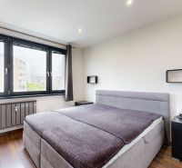 Schlafzimmer in einer 4-Zimmer-Wohnung mit großem Fenster und Boden in Holzoptik.