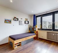 Kinderzimmer mit Bett und Fenster mit Aussicht; 4-Zimmer-Wohnung mit Holzboden-Dekor.