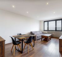 Wohnzimmer mit Sitzgelegenheiten, Tisch und Holzboden in einer 4-Zimmer-Wohnung.