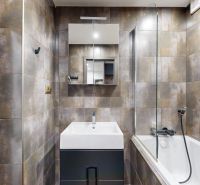 Badezimmer in einer 4-Zimmer-Wohnung mit Badewanne, Waschbecken und Waschmaschine in stilvollen Fliesen.