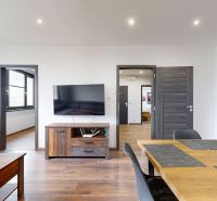 Innenraum einer 4-Zimmer-Wohnung mit Holzboden, Fernseher und Holzmöbeln.