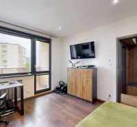 Ein Zimmer in einer 4-Zimmer-Wohnung mit einem Holzboden, einem Schreibtisch und einem Fernseher.