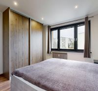 Schlafzimmer in einer 4-Zimmer-Wohnung mit Holzboden, Kleiderschrank und Fenster.