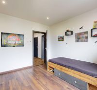 Kinderzimmer mit Bett, Regalen und Boden in Holzoptik in einer 4-Zimmer-Wohnung.