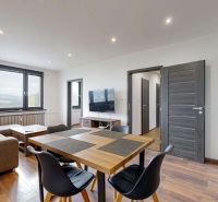 Wohnzimmer in einer 4-Zimmer-Wohnung mit Sofa, Esstisch und Holzboden.