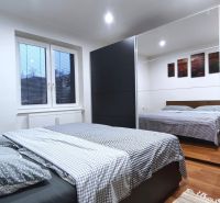 Ein Schlafzimmer in einem Einfamilienhaus mit einem Bett, einem großen Schrank und einem Boden in Holzoptik.