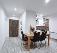 Esszimmer in einem Einfamilienhaus mit Holztisch, schwarzen Stühlen und Küchenzeile.