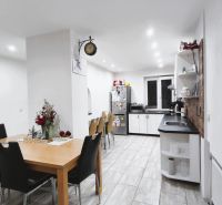 Küche in einem Einfamilienhaus mit Esstisch, schwarzen Stühlen und hellem Boden.
