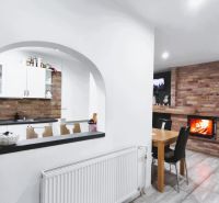 Küche und Wohnzimmer in einem Einfamilienhaus mit einem gemauerten Kamin und einem gewölbten Fenster.