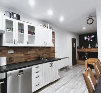 Küche in einem Einfamilienhaus mit ländlicher Ziegelverkleidung und weißen Schränken, Boden mit Holzdekor.