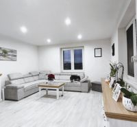Wohnzimmer in einem Einfamilienhaus mit Sofa, Dekorationen und Holzboden.
