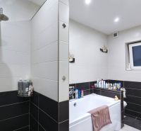 Ein Badezimmer im Einfamilienhaus mit Badewanne, Dusche und weißen Fliesen.