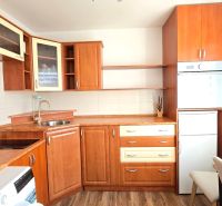 Die Küche einer Einzimmerwohnung mit Holzschränken und einem Boden in Holzoptik.