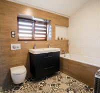 Ein Badezimmer in einem Einfamilienhaus mit einer Badewanne, einem Waschbecken und einem Boden mit Holzdekor.