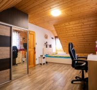 Dachzimmer mit Holzverkleidung an der Decke, Bett, Schrank und Boden mit Holzdekor.