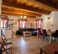 Wohnzimmer eines Einfamilienhauses mit Holzdecken, einem Boden in Holzoptik und roten Vorhängen.