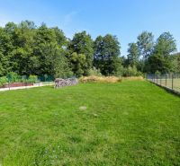 Der Garten des Einfamilienhauses in Očová mit Rasen und Umzäunung, umgeben von Wald.