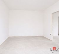 Leerer Raum in einer 4-Zimmer-Wohnung mit weißen Wänden und Betonboden.