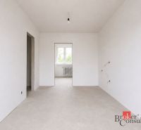 Ein leerer Raum in einer Vierzimmerwohnung mit weißen Wänden und einem Fenster.