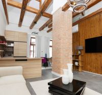 Wohnzimmer in einer 3-Zimmer-Wohnung mit sichtbaren Balken und einer Ziegelsteinsäule.