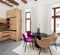 Küchenecke in einer 3-Zimmer-Wohnung mit bunten Stühlen und einem Boden in Holzoptik.