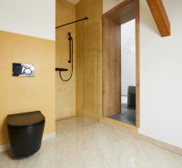 Badezimmer mit gelben Wänden, schwarzer Toilette und Duschkabine in einer 3-Zimmer-Wohnung.
