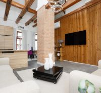 Wohnzimmer mit Ziegelwand, Holzboden und bequemen Sesseln in einer 3-Zimmer-Wohnung.