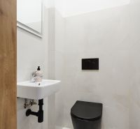 Badezimmer mit schwarzer Toilette, Waschbecken und Spiegel in einer 3-Zimmer-Wohnung.