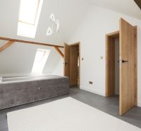 Helles Schlafzimmer mit Bett, schrägen Dachfenstern und Holzelementen in einer 3-Zimmer-Wohnung.