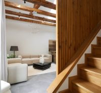 Eine Treppe mit einem Boden in Holzoptik, die in das Wohnzimmer einer 3-Zimmer-Wohnung führt.