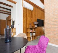 Innenraum einer 3-Zimmer-Wohnung mit Ziegelwand, Holzboden und bunten Möbeln.