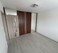 Ein leerer Raum in einer 3-Zimmer-Wohnung mit Holzboden und Einbauschrank.